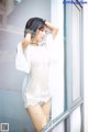 A woman in a white lingerie leaning against a window.