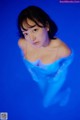 A woman in a blue dress is standing in the water.