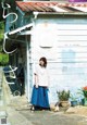 A woman standing in front of a white building.