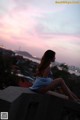 A woman sitting on top of a building looking out over a city.