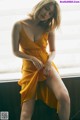 A woman in a yellow dress sitting on a window sill.