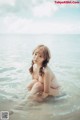 A woman sitting in the water on a beach.