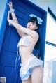 A woman in a blue and white lingerie leaning against a blue door.