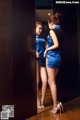 A woman in a blue dress standing in front of a mirror.