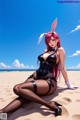 A woman in a bunny costume sitting on a beach.