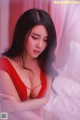 A woman in a red lingerie sitting on a bed.