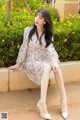 A woman sitting on a bench in a white dress.