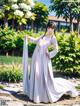 A woman in a white dress standing in a garden.