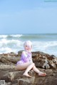 A woman sitting on a rock by the ocean.