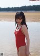 A woman in a red bathing suit standing in the water.